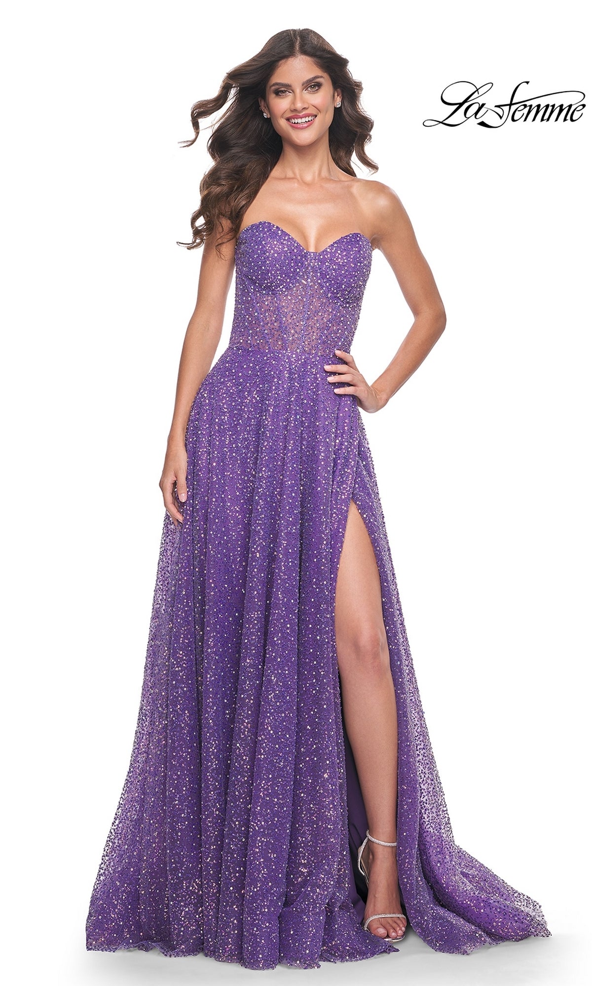 A woman wears the La Femme Strapless Embellished Prom Dress 32136, a purple glitter A-line gown with hot-stone details and a thigh-high slit, paired with silver heels, standing against a white background. The La Femme logo appears in the top right corner.